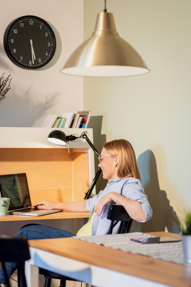 A woman sitting in her home office leaning back in a desk chair working.